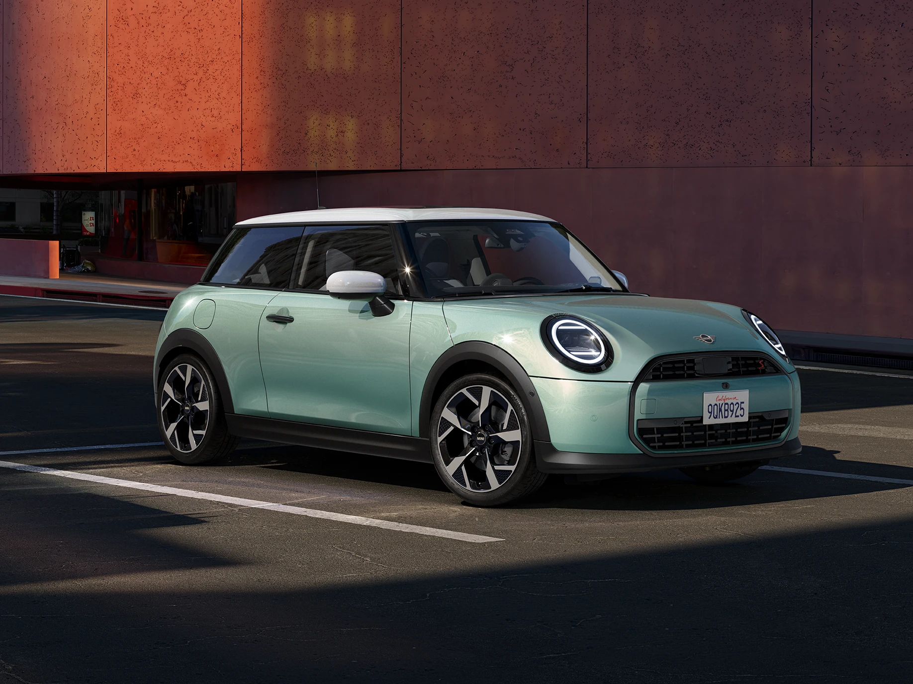Вид спереду збоку на MINI Cooper у кольорі Ocean Wave Green з білим дахом.