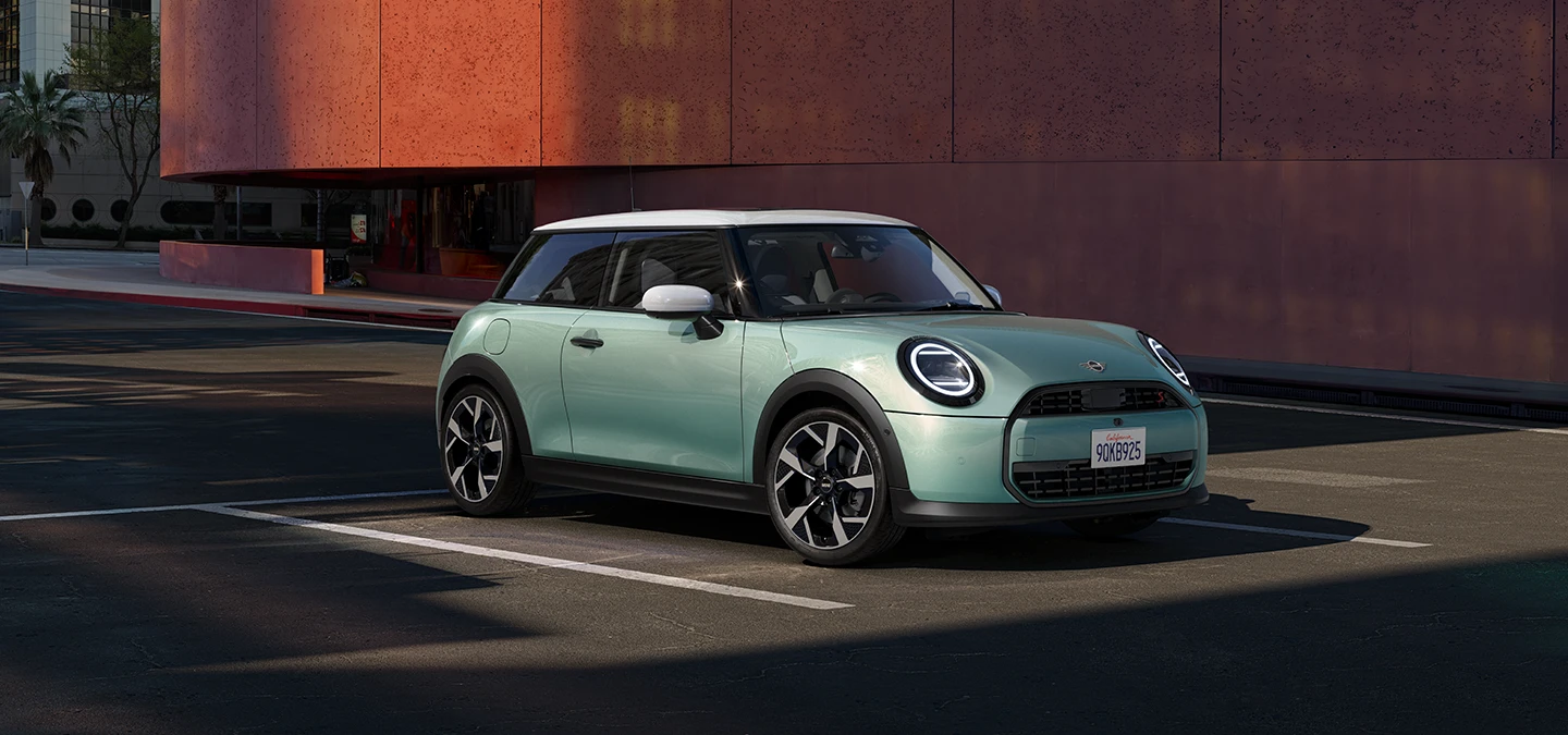 Вид спереду збоку на MINI Cooper у кольорі Ocean Wave Green з білим дахом.