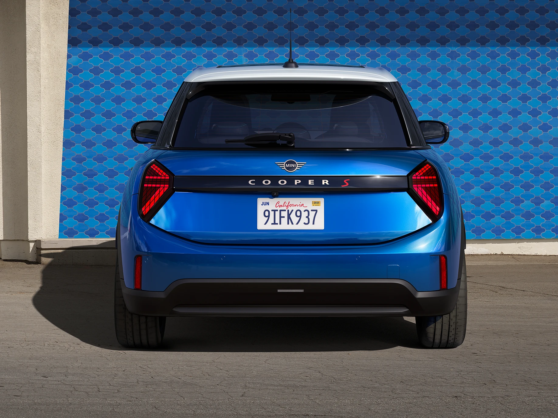 Вигляд ззаду 5-дверного MINI Cooper у кольорі Icy Sunshine Blue та Multitone Roof Blue.