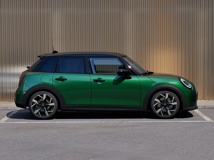 Бічний вигляд 5-дверного MINI Cooper у кольорі British Racing Green із дахом у чорному кольорі.