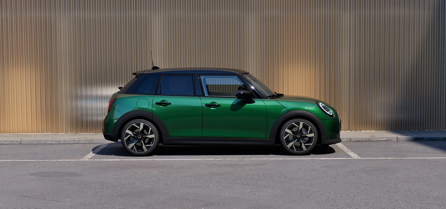 Бічний вигляд 5-дверного MINI Cooper у кольорі British Racing Green із дахом у чорному кольорі.