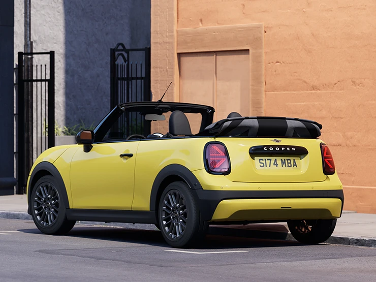 Вигляд ззаду ліворуч MINI Cooper Convertible кольору Sunnyside Yellow.