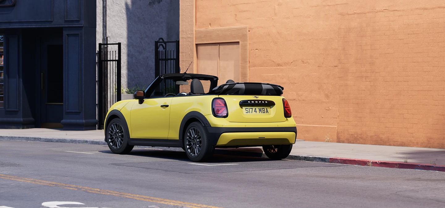 Вигляд ззаду ліворуч MINI Cooper Convertible кольору Sunnyside Yellow.
