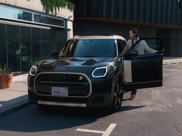 Повністю електричний MINI Countryman в кольорі Midnight Black і з яскравим сріблястим дахом - вигляд спереду.