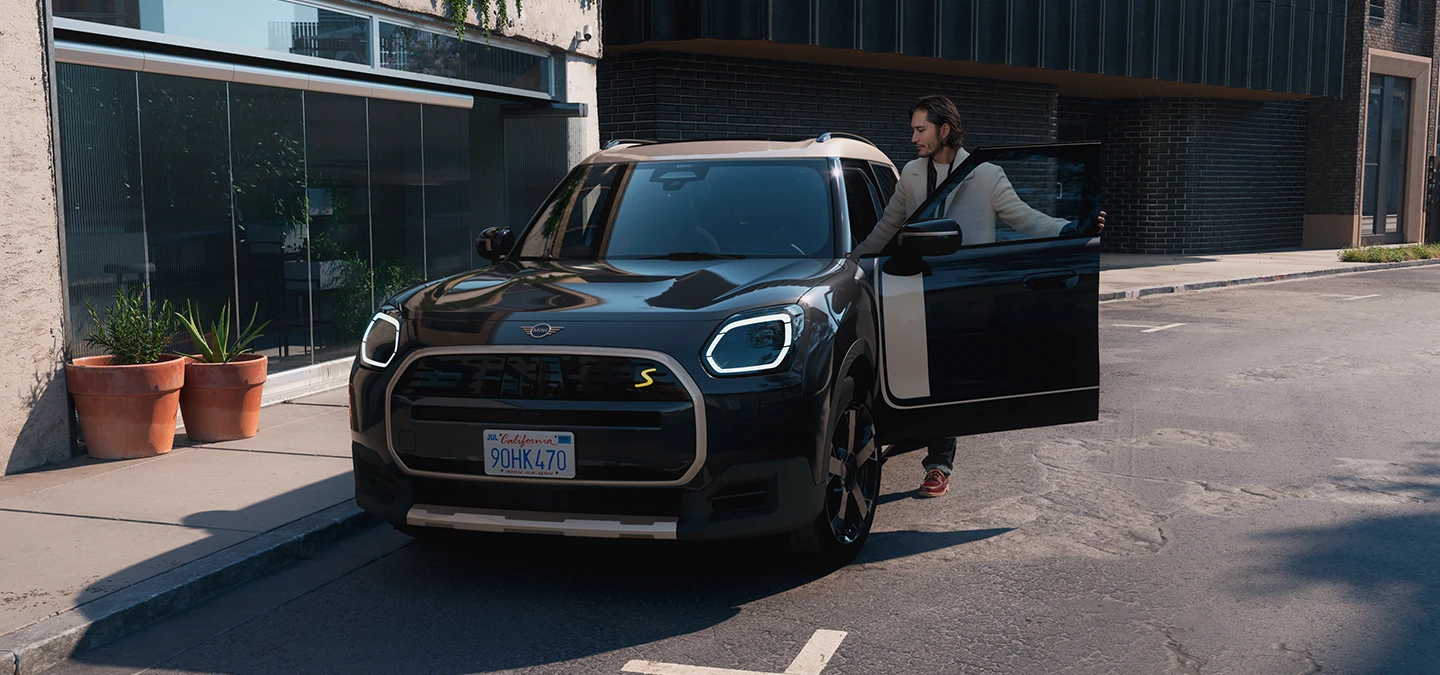 Повністю електричний MINI Countryman в кольорі Midnight Black і з яскравим сріблястим дахом - вигляд спереду.