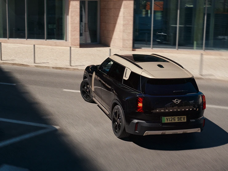 Повністю електричний MINI Countryman в кольорі Midnight Black і з яскравим сріблястим дахом - вигляд ззаду.