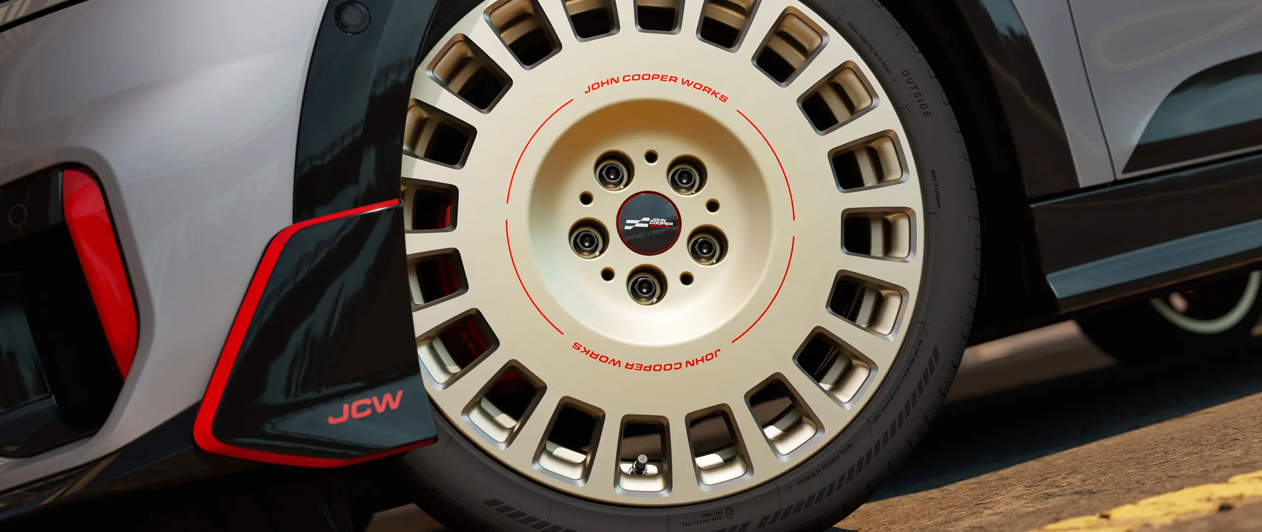 Крупний план деталей колеса JCW Rallye Spoke 964 діаметром 18 дюймів у двоколірному виконанні Vibrant Silver із алмазною обробкою та переднім крилоподібним елементом.