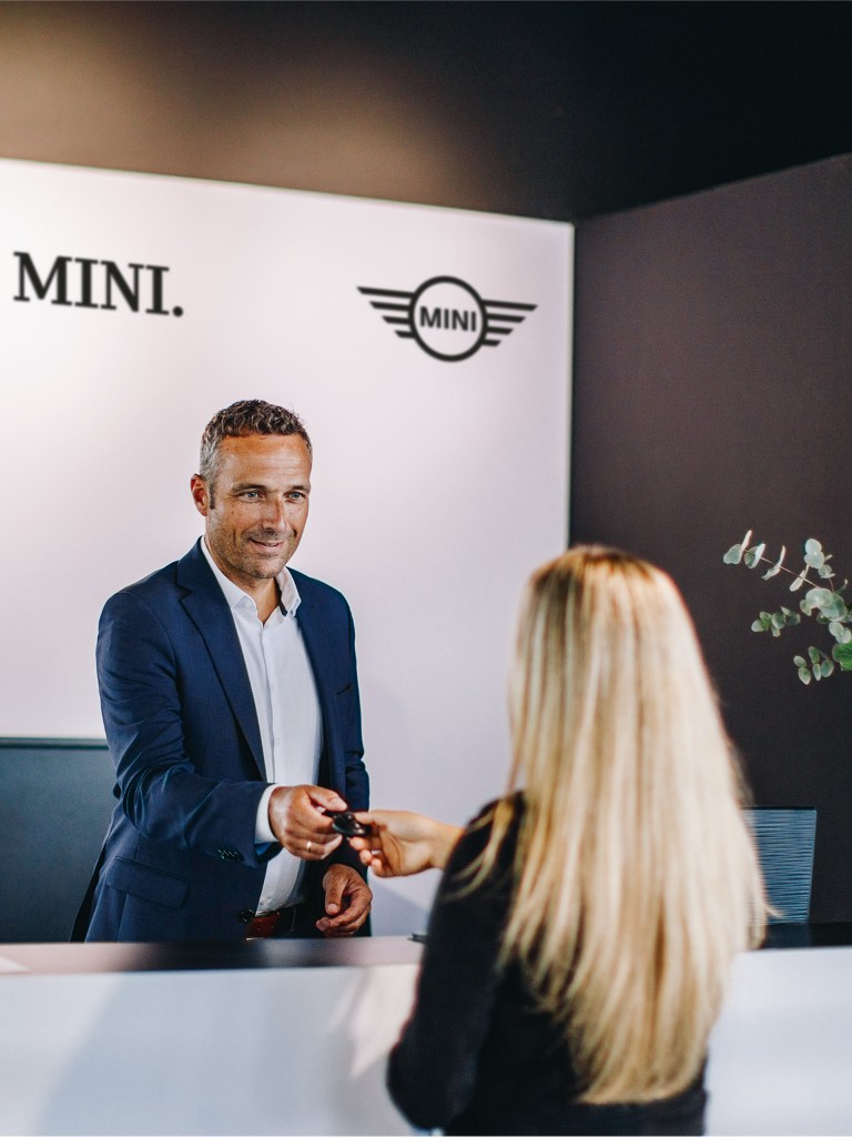 Представник MINI SERVICE передає ключі від машини білявці в одному із сервісних центрів MINI